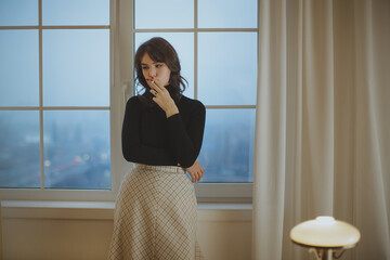 Stylish Young Woman Smoking Thoughtfully By Window In Cozy Room 