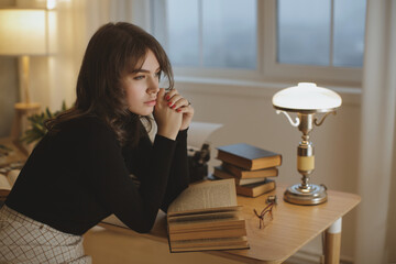 Thoughtful Young Woman Leaning On Desk With Books In Cozy Study Room 