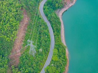 Winding mountain road by a green forest lake