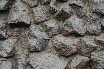 A close-up view of a rough stone wall, showcasing natural, uneven rocks fitted together.