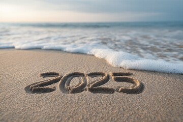 Waves gently wash over sandy beach, revealing year 2025 etched i