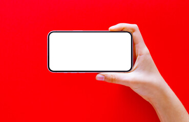 Mobile phone horizontally in hand on red background