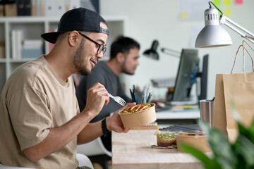 Young Asian man eating healthy meal while working, Businessman having a lunch break at the office