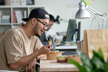 Young Asian man eating healthy meal while working, Businessman having a lunch break at the office