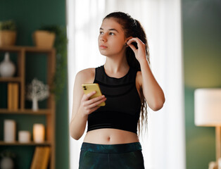 Young woman is wearing wireless headphones using her smartphone