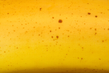 A close-up shot of a yellow banana peel with small brown spots, showing its natural texture