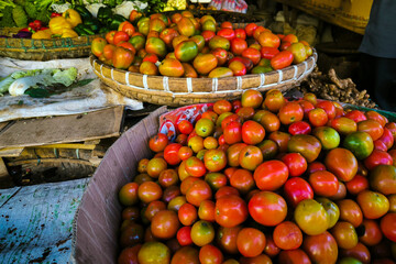 A pile of fresh red and yellow tomatoes on a container at a traditional market.