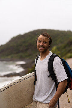Young man carrying surfboard and walking to beach