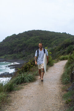 Young man carrying surfboard and walking to beach