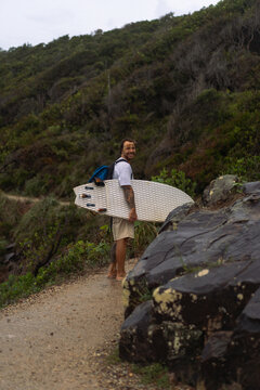 Young man carrying surfboard and walking to beach
