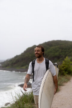 Young man carrying surfboard and walking to beach