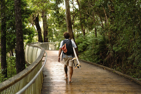 Young man carrying surfboard and walking to beach