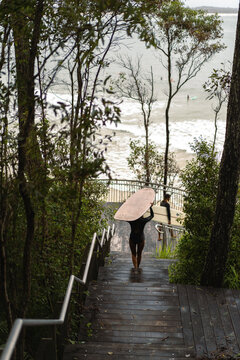 Peoples walks towards the beach with a surfboards