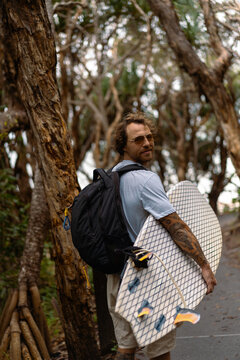 Young man carrying surfboard and walking to beach