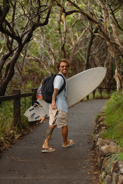 Young man carrying surfboard and walking to beach