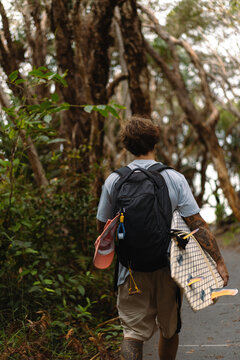 A middle aged man walks towards the beach with a surfboard