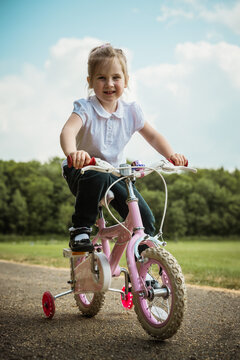 Little girl riding a pink bike in the park