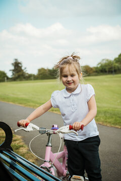 Little girl with a pink bike in the park