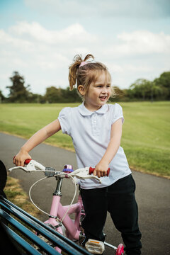 Little girl with a pink bike in the park