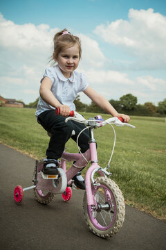 Little girl riding a pink bike in the park