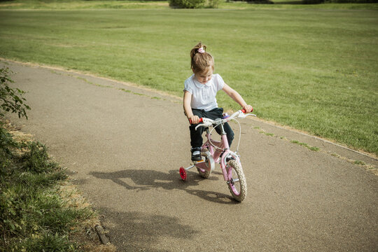Little girl riding a pink bike in the park. Copy space.