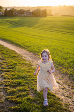 Running little girl, having fun in the field, sunset