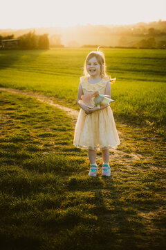Little girl smiling and holding a windmill, sunset