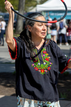 Indigenous instructor demonstrates hoop dance moves at a street event.