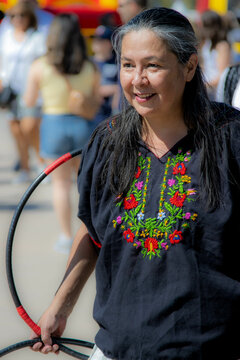 Indigenous performer demonstrates a hoop dance posture at a festival.