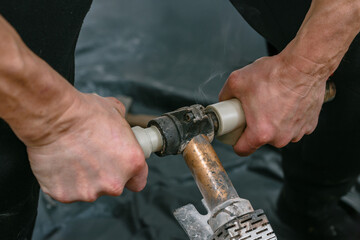 Professional male plumber soldering plastic water pipeline. Worker using a pipe cutter and...