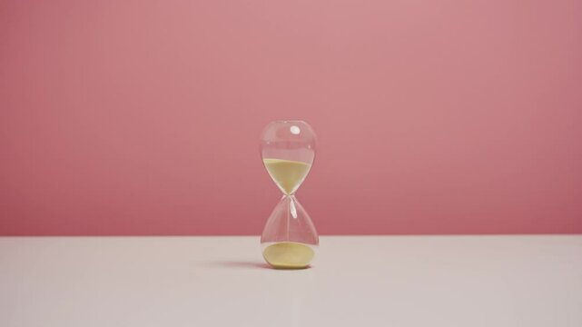 Hourglasses on table with isolated pink background.