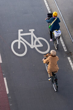 Two cyclists sharing the road in Copenhagen, blue bike lanes, environmental awareness, clean commuting, and modern Nordic city infrastructure