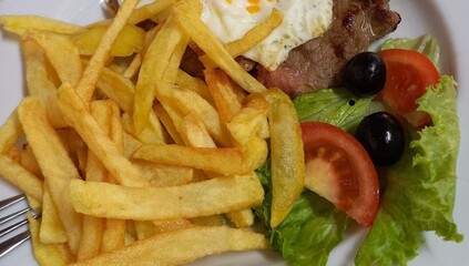 Healthy food. French fries with meat, tomato, olives and salad