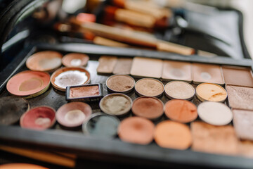 Close-up of a colorful, well-used makeup palette with various shades of powders, blushes, and...