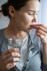 Asian pregnant woman is taking pills and vitamins for pregnant women with capsule on her hand and water. Drinking a tablet with a glass of water. 