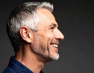 Fototapeta premium Profile of a smiling, middle-aged man with graying hair and beard against a dark background
