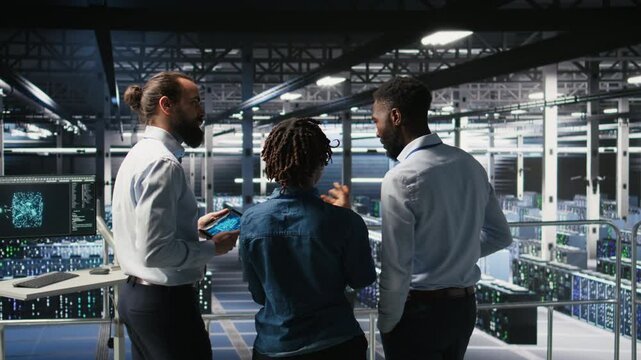 Data center manager talking with workers performing maintenance on supercomputers used for AI. Server hub team leader and staff members upgrading rigs used for deep learning training, camera A