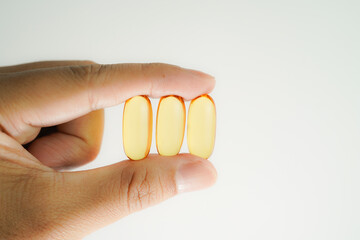 Male hand holding Oil filled capsules, softgel of food supplements, fish oil, omega 3, vitamin E