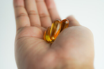 Male hand holding Fish oil capsules with omega 3, omega 9, vitamin D, vitamin E, Cod liver oil