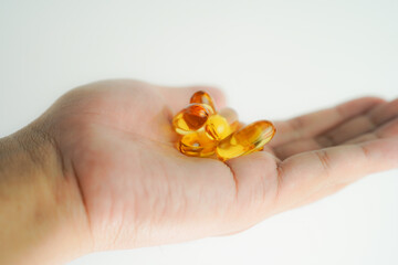 Male hand holding Fish oil capsules with omega 3, omega 9, vitamin D, vitamin E, Cod liver oil