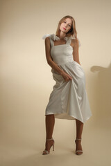 Serie of studio photos of female model in elegant white midi dress with bows on shoulder straps	