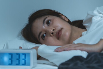 Young woman sleepless during night time on the bed.
