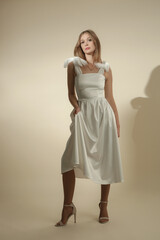 Serie of studio photos of female model in elegant white midi dress with bows on shoulder straps	
