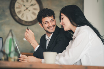 Caucasian Hispanic man discussing work with woman at office desk. male and female working together....