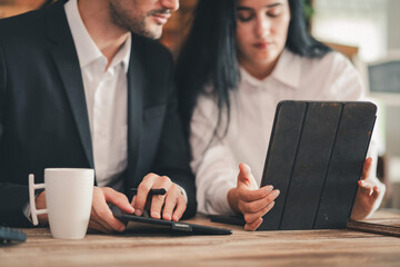 Two business professionals in office loft style using digital tablets discussing or meeting. Hispanic man and woman collaborating on work project. small business, lifestyle working in home office