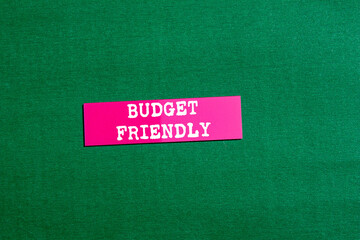 Budget friendly message written on pink paper sticker on green background. Conceptual budget friendly symbol. Copy space.