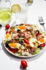 Appetizing Salad with iceberg, tuna, boiled eggs in a white plate on the table. Healthy breakfast