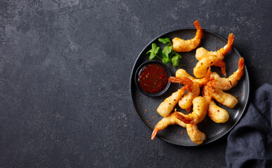 Shrimp tempura with sauce on a black plate. Dark grey background. Copy space. Top view.