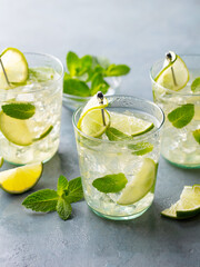 Gin fizz cocktail with lime and mint, lemonade, ice tea in glasses. Close up.