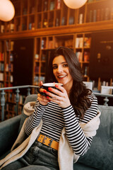 Young woman enjoys coffee in cozy bookstore cafe on a relaxed afternoon with books around